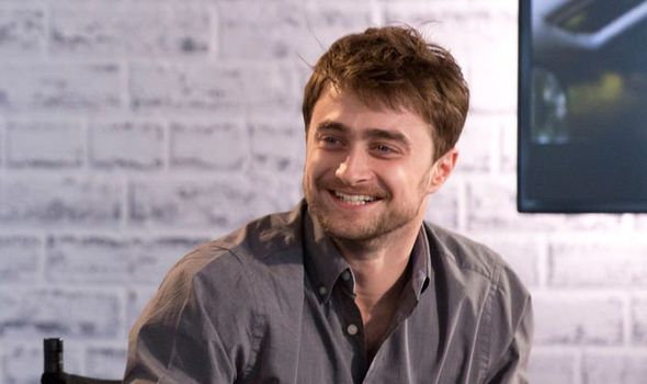 Daniel Radcliffe menggunakan kemeja warna cokelat sedang tersenyum